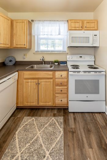 a kitchen with white appliances and wooden cabinets at Seven Oaks Townhomes, Edgewood, MD